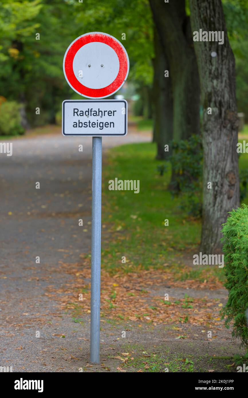 A traffic sign at the entrance of a cemetery with the German addition cyclists dismount Stock Photo
