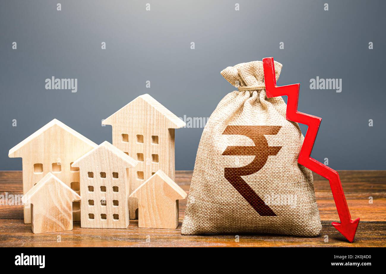 Houses and indian rupee money bag with down arrow. Falling of real estate market prices. Reducing maintaining cost, energy efficiency, saving. Realty Stock Photo