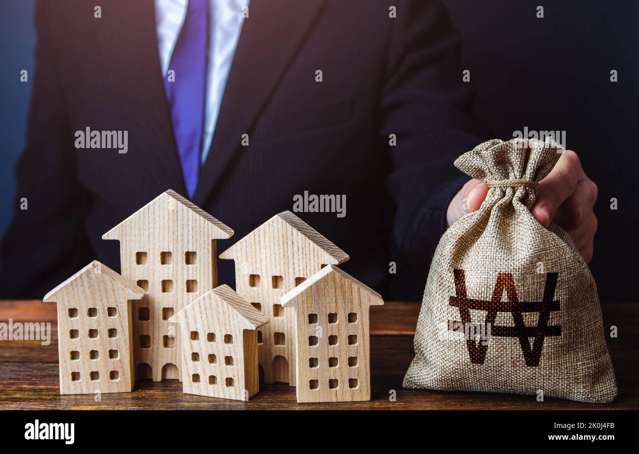 A businessman puts a south korean won money bag near the houses. Construction industry, rental business and hotel tourism. Investments in real estate Stock Photo