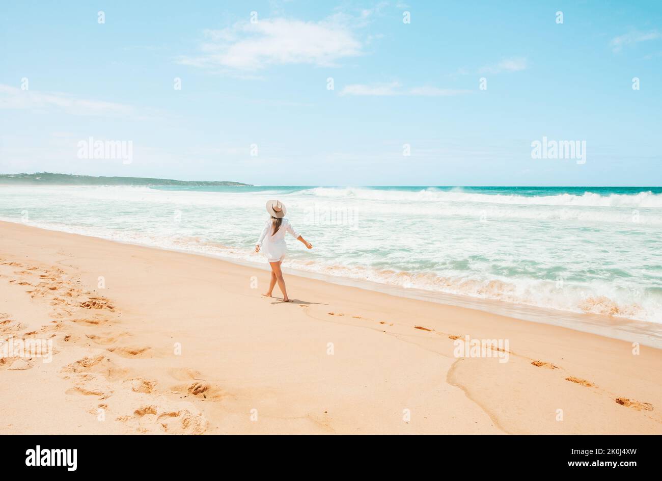 Woman in white walking along the beach on beautiful summer day in Australia Stock Photo