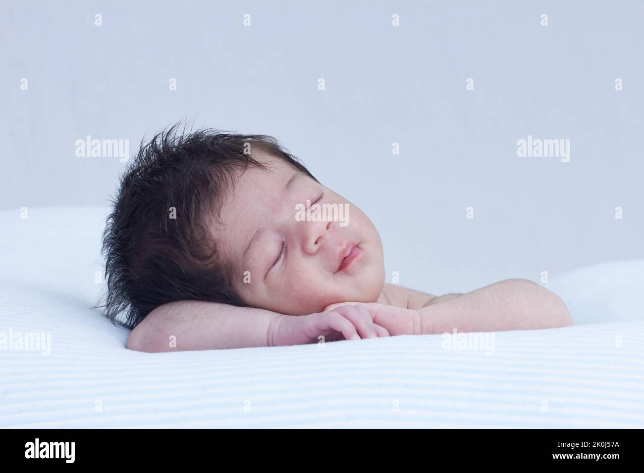 Baby infant sleeping on a cushion , resting her head on her arms in a