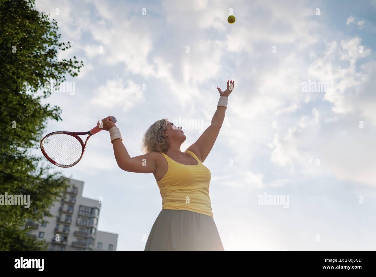 Just serve it. Shot of a mature woman playing tennis outside. Stock Photo
