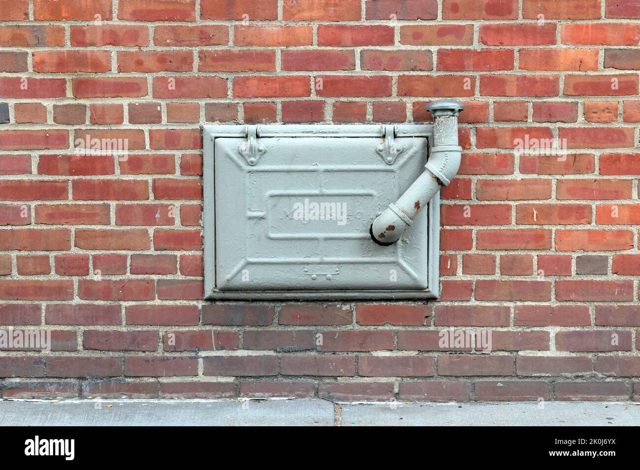 A Majestic coal chute cast iron door with a home heating oil pipe sticking out in a new york city apartment building. Stock Photo