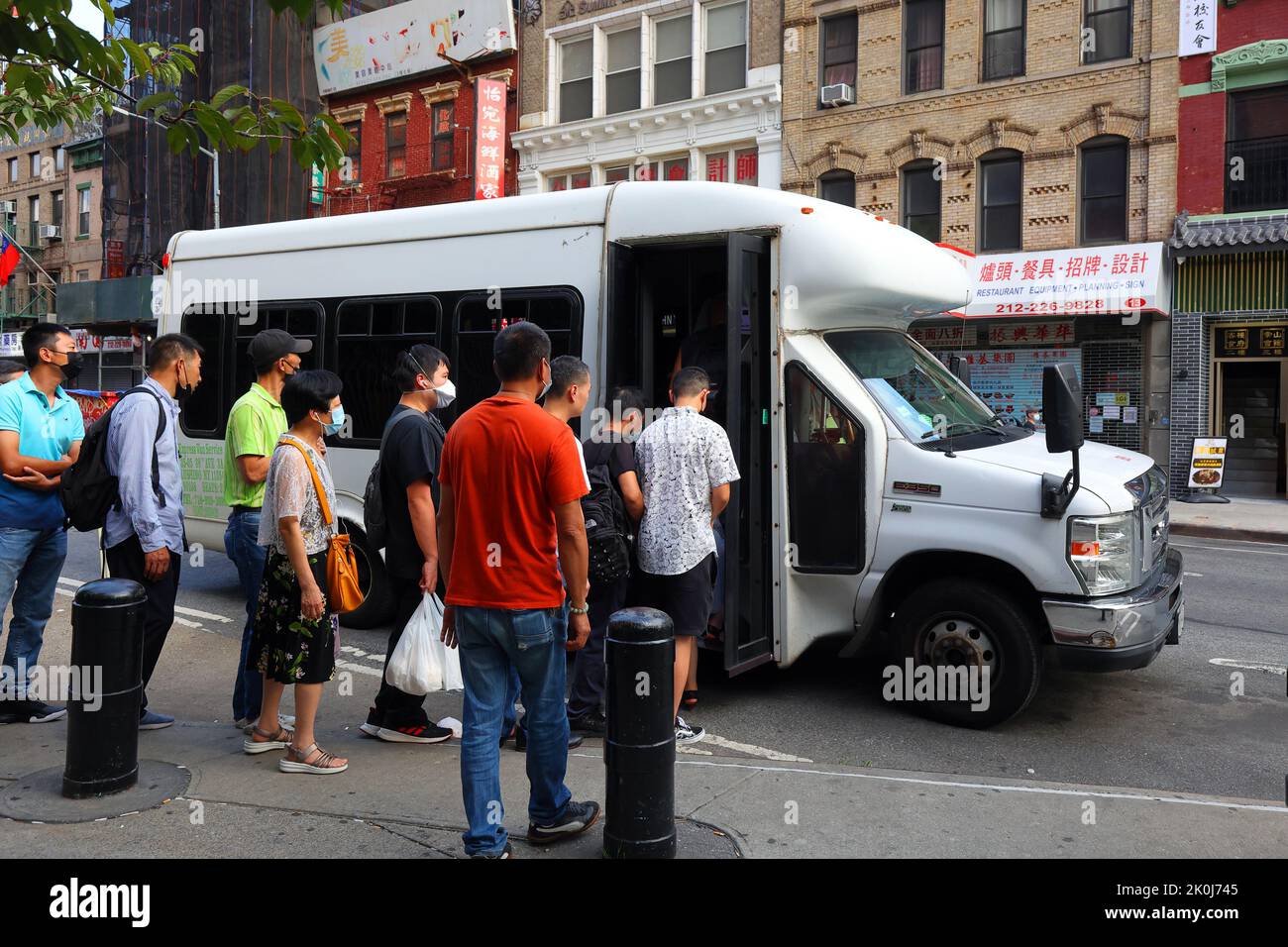 Asian people of Chinese descent in Manhattan Chinatown boarding a dollar van express shuttle bus transportation service to Flushing Chinatown. Stock Photo