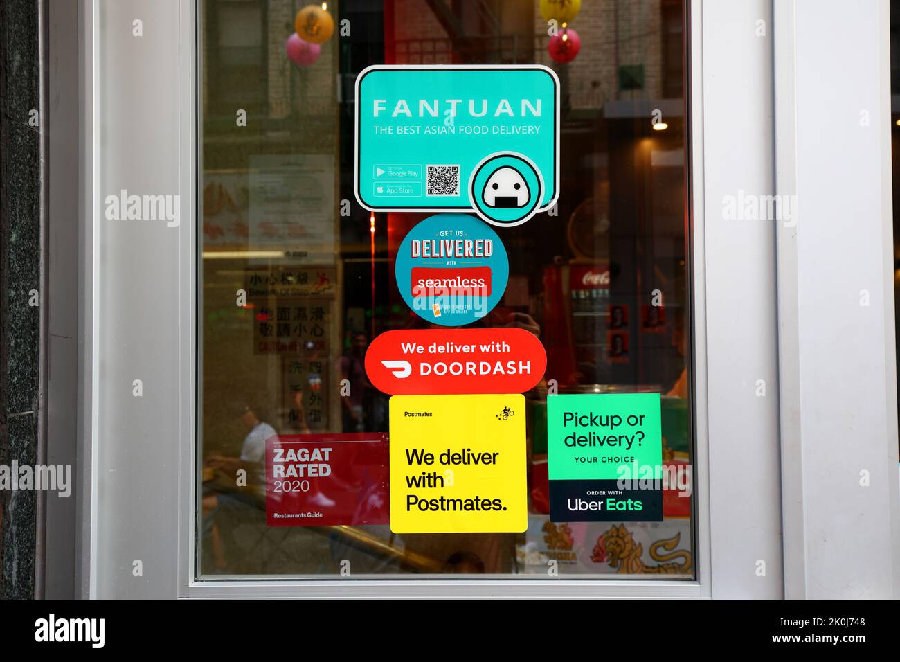 Fantuan Delivery, Seamless, Doordash, Postmates, and Uber Eats food delivery service app stickers on a door to a restaurant in Chinatown, New York. Stock Photo