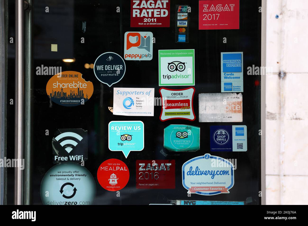 Delivery service apps, and restaurant advertising stickers on the door to a restaurant in New York Stock Photo