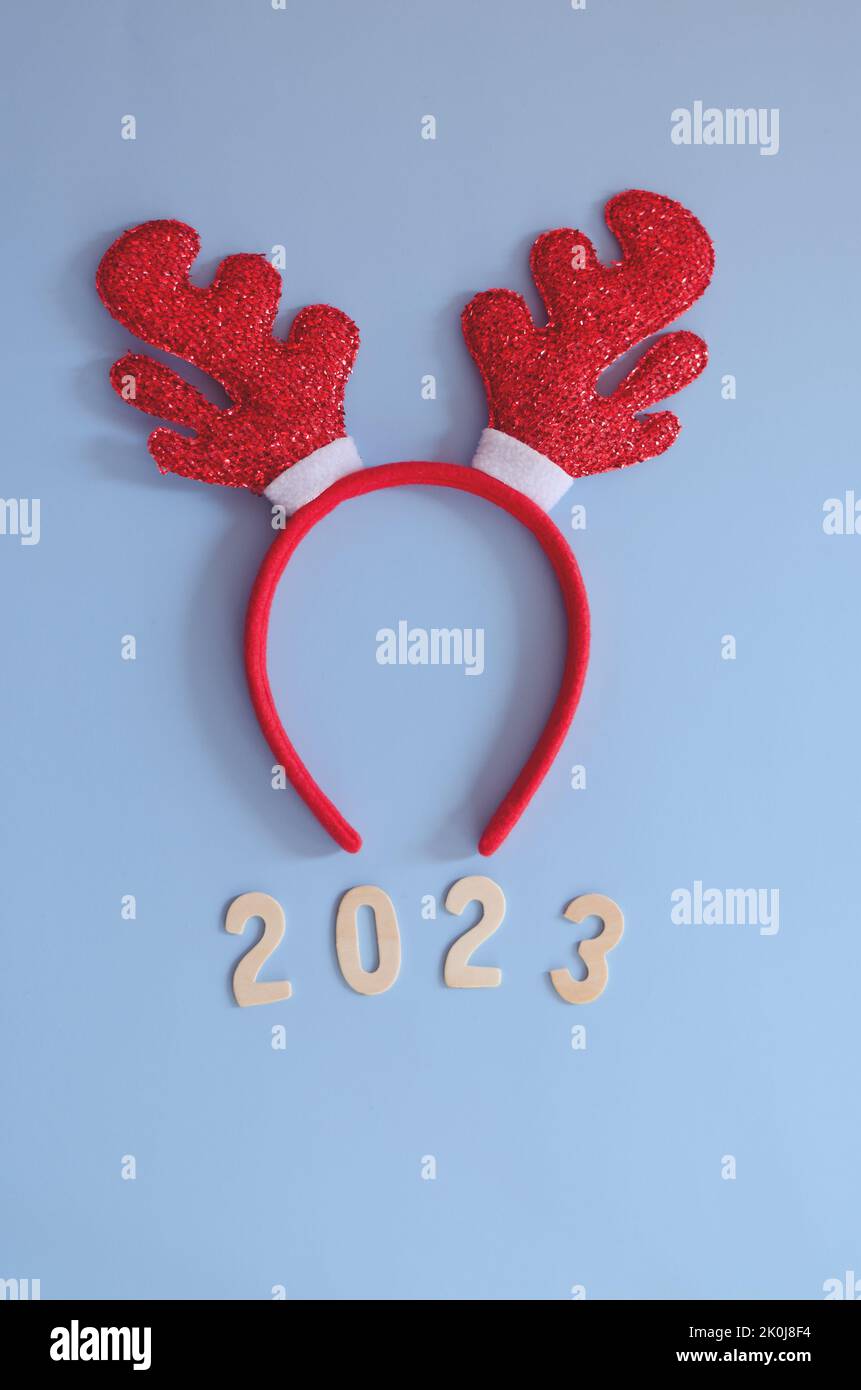 Top view of numbers 2023. Red cartoon deer horns close up. Blue background. New year, Christmas  celebration. Stock Photo