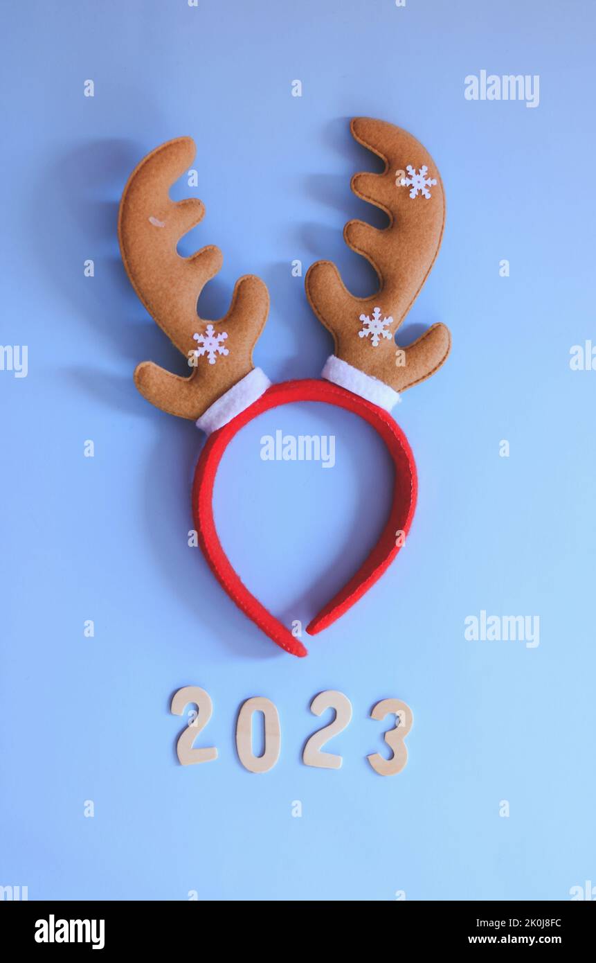 Top view of numbers 2023. Red cartoon deer horns close up. Blue background. New year, Christmas  celebration. Stock Photo