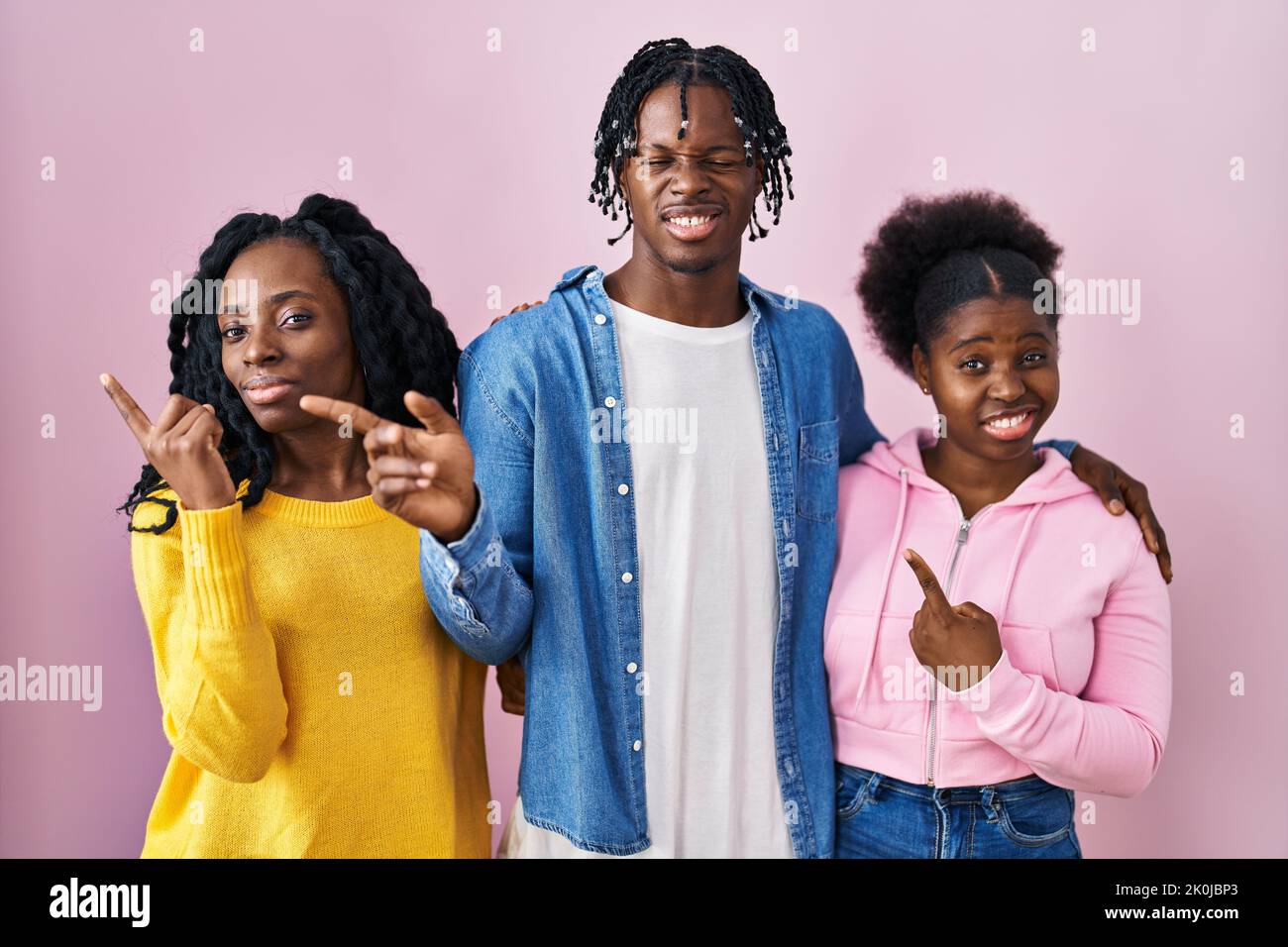 Group of three young black people standing together over pink ...