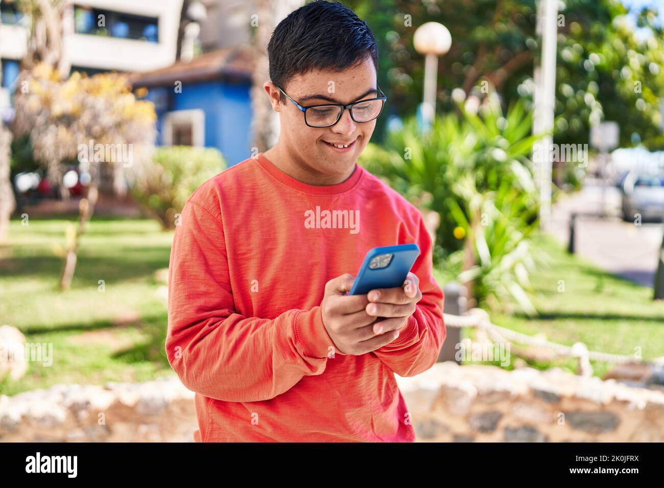 Down syndrome man smiling confident using smartphone at park Stock Photo