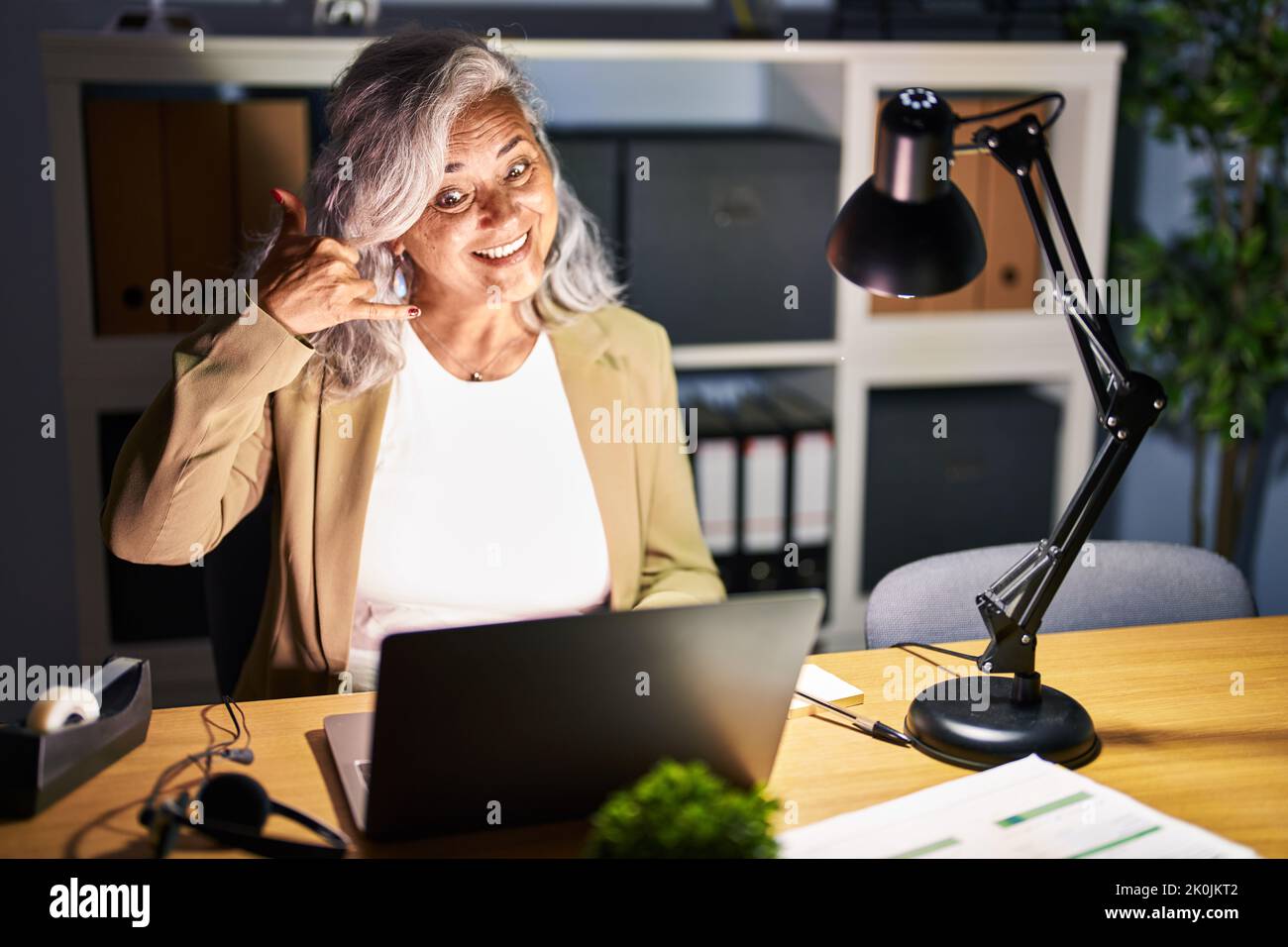Middle age woman with grey hair working using computer laptop late at ...