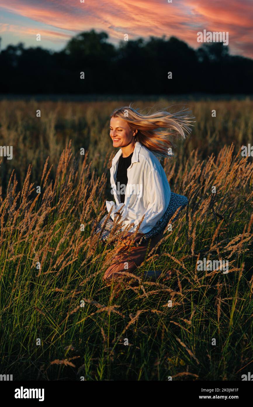 Radiant young blond woman, running through a wheat field. Stock Photo