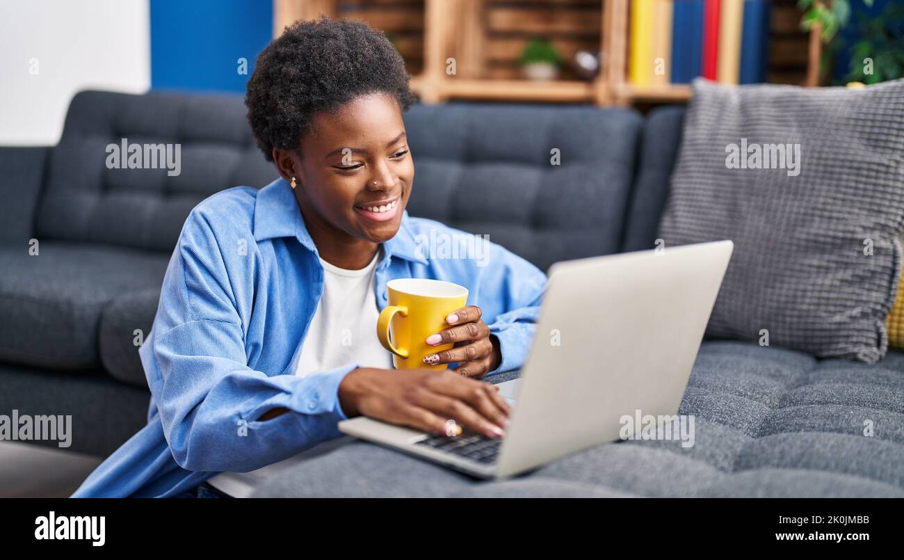 African american woman using laptop and drinking coffee sitting on ...