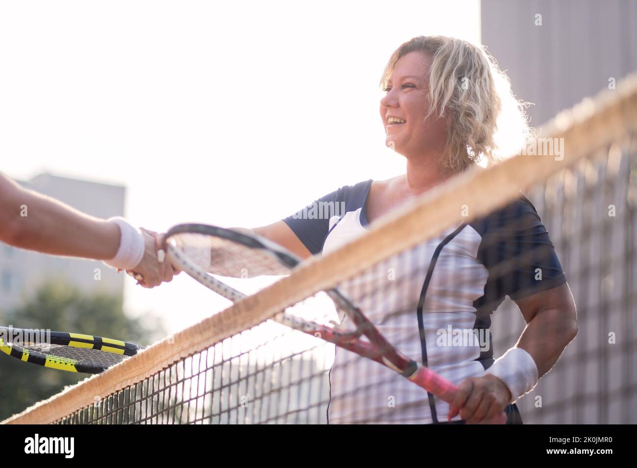 Mature woman shaking hand after playing tennis outside. Stock Photo