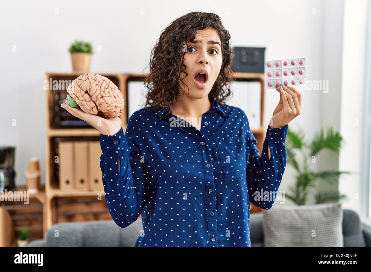 Young woman holding brain and pills as mental health concept
