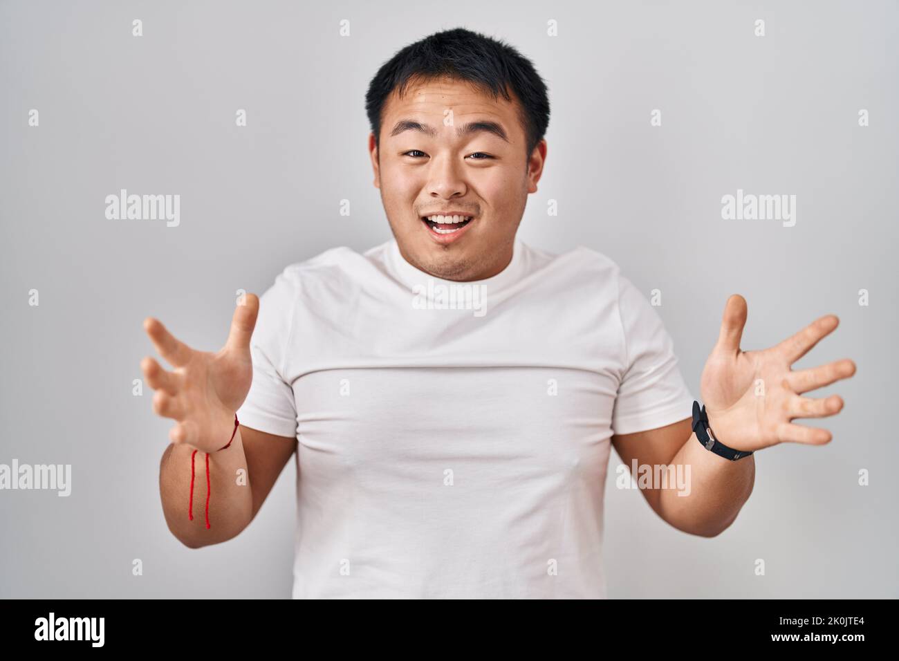 Young chinese man standing over white background celebrating crazy and amazed for success with arms raised and open eyes screaming excited. winner con Stock Photo