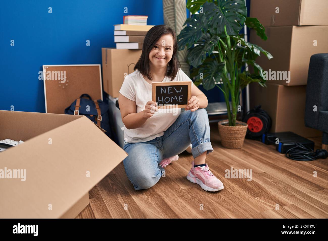 Hispanic girl with down syndrome sitting on the floor at new home celebrating crazy and amazed for success with open eyes screaming excited. Stock Photo