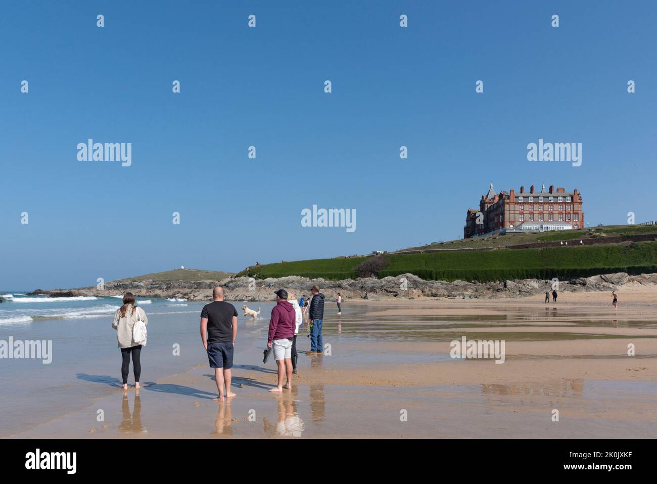 Holidaymakers visitors standing on Fistral Beach and enjoying the warm sunny weather in Newquay in Cornwall in the UK. Stock Photo
