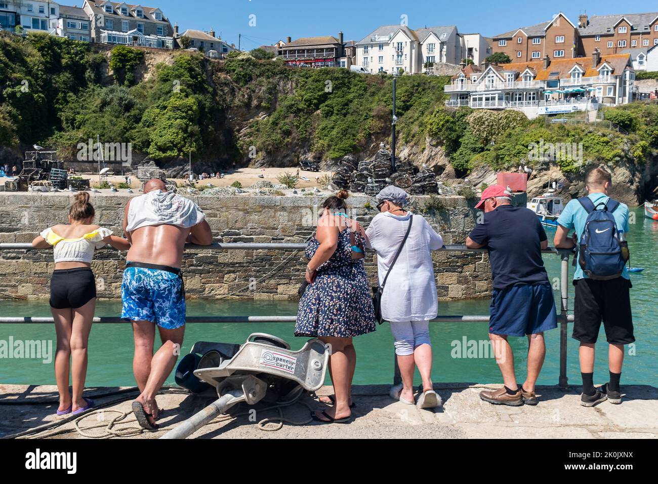 Tourists Holidaymakers Visitors standing on the quay in the picturesque Newquay Harbour Harbor In Cornwall in England in the UK. Stock Photo