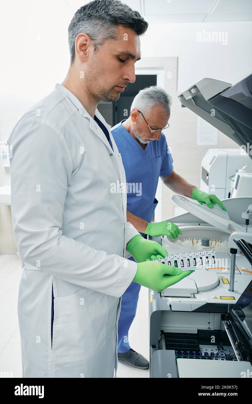 Laboratory technicians working in medical laboratory and researching on blood samples using modern technology and medical research machines Stock Photo