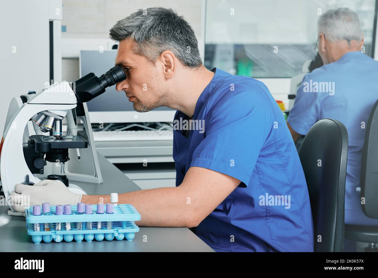 Two male scientists looking in microscopes while working on medical blood research in science medical lab Stock Photo