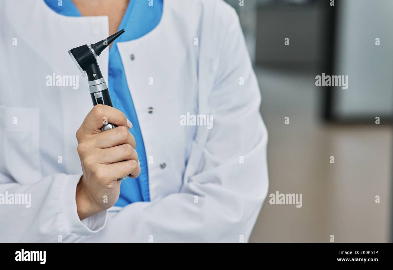 ENT doctor with otoscope in hands standing in audiology office. Audiologist consultation, deafness treatment, selection of hearing aids Stock Photo