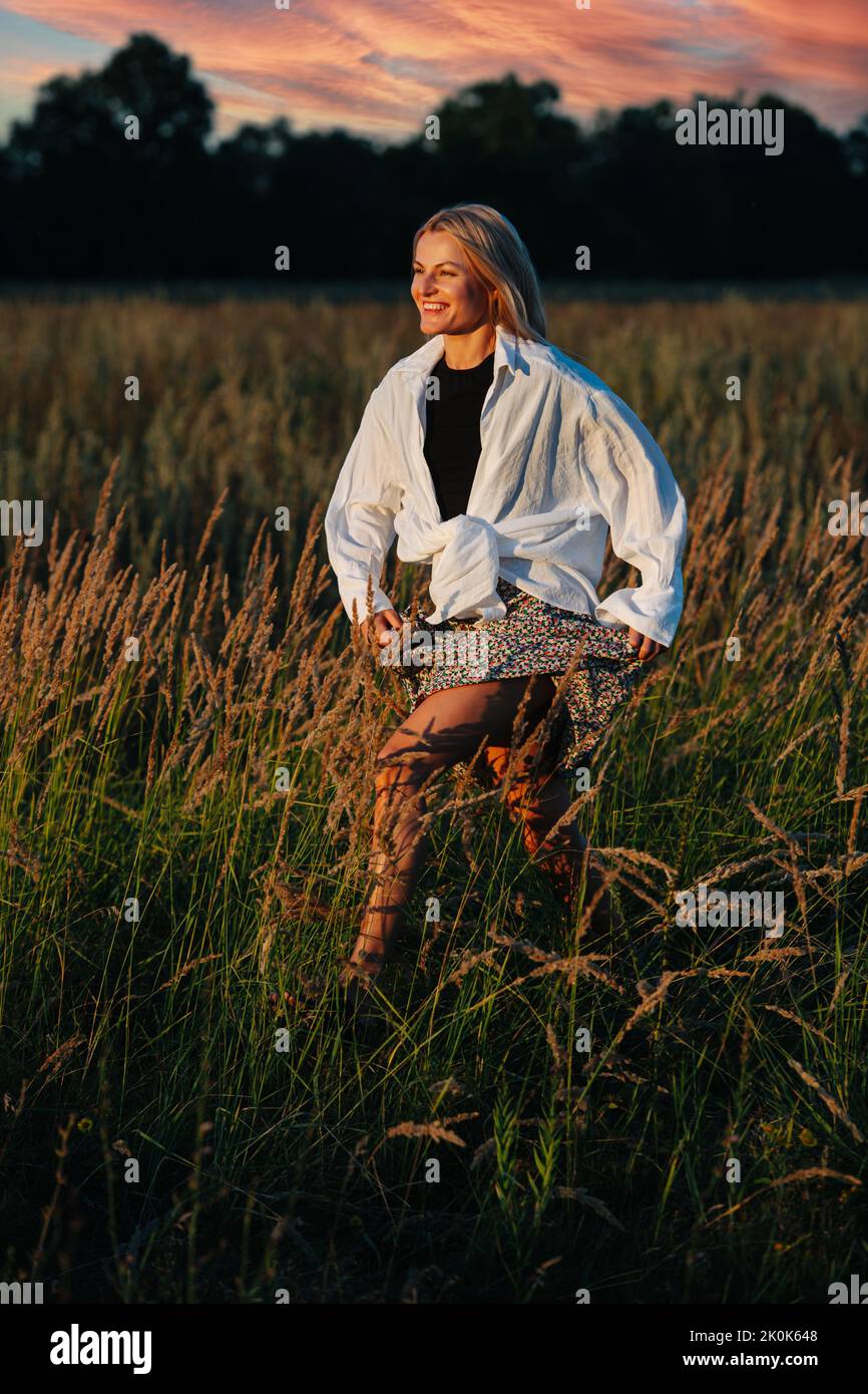 Smiling young blond woman, running through a wheat field. Stock Photo