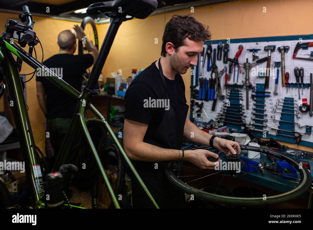 Technician with dirty hands fixing bicycle wheel while working in workshop Stock Photo