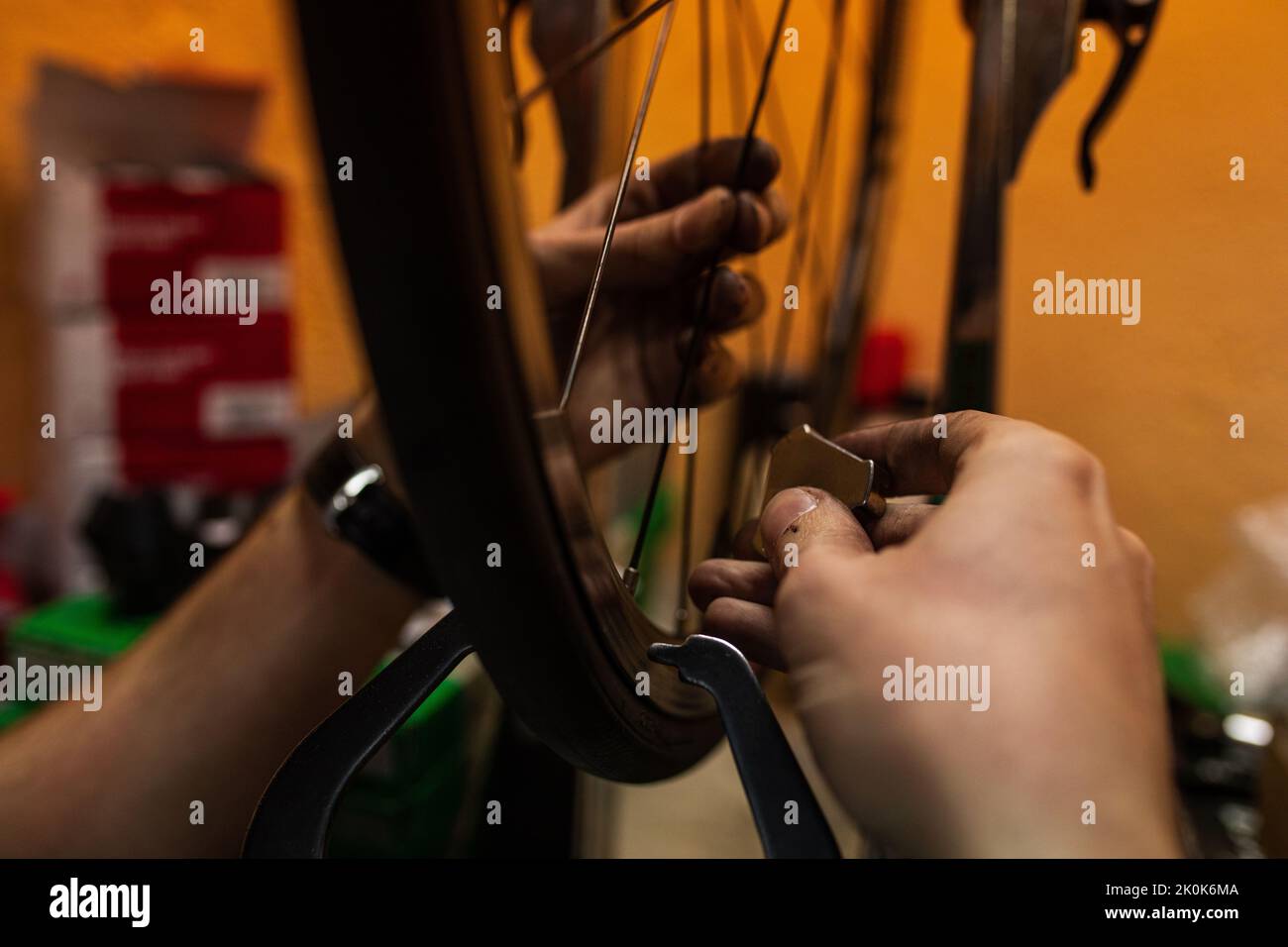 Technician with dirty hands fixing bicycle wheel while working in workshop Stock Photo