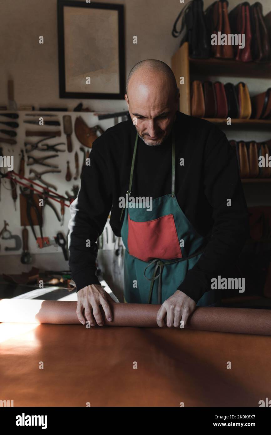 Man wrapping leather fabric in atelier Stock Photo - Alamy