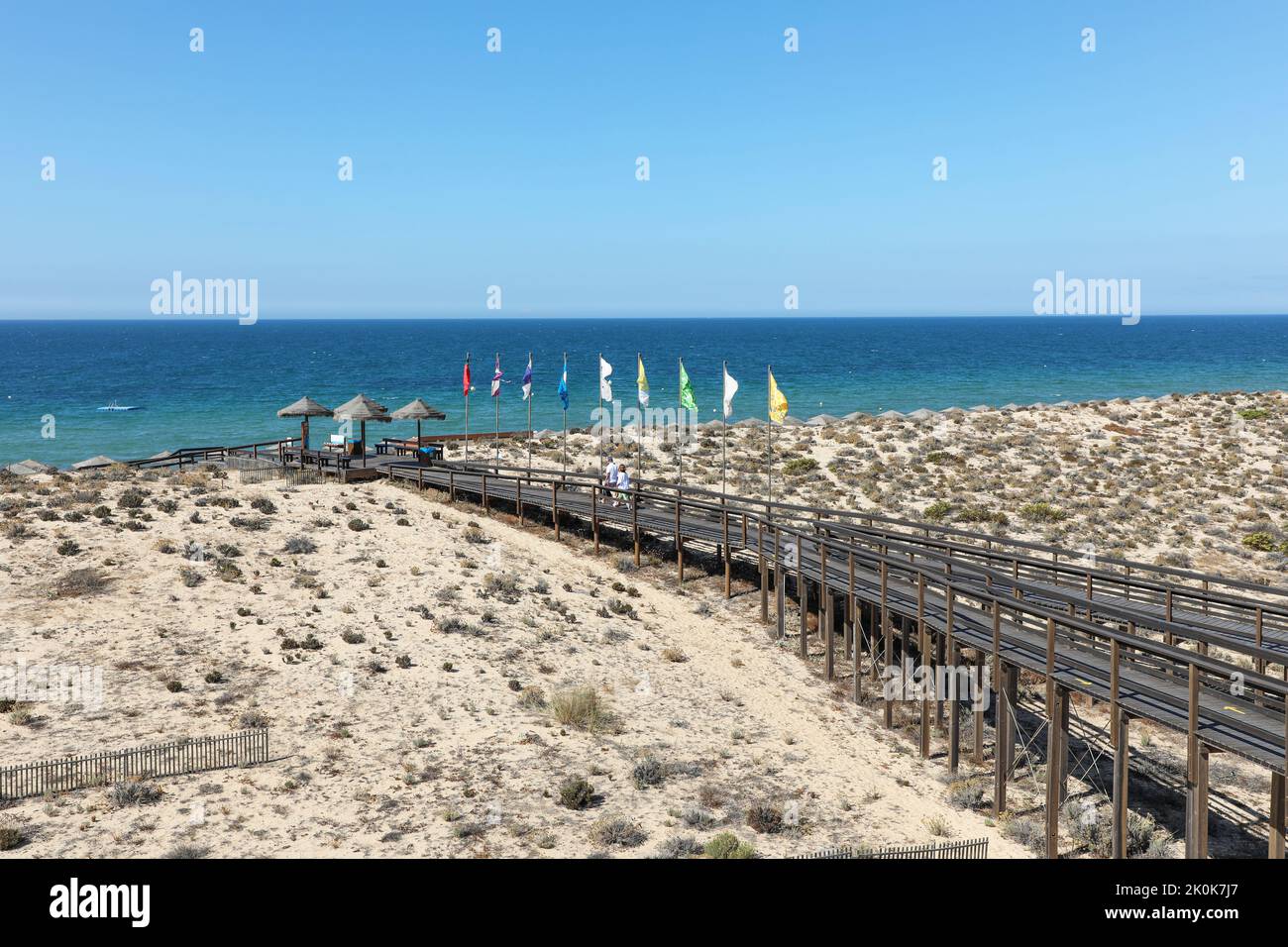 Tourists walking on the wooden walkway towards the beach and across the