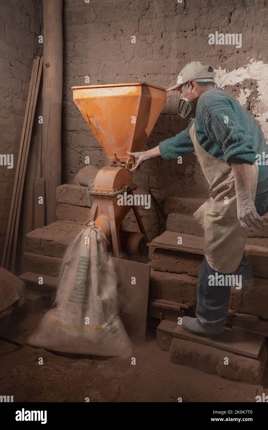 Full body side view of male worker in uniform and respirator standing near industrial plaster station in professional ceramic workshop Stock Photo