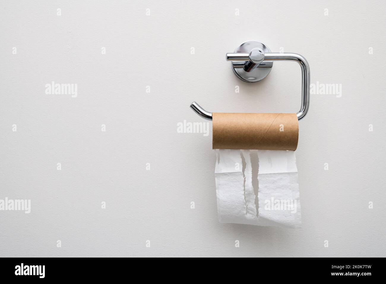 Finished toilet paper empty roll hanging on the wall. Stock Photo