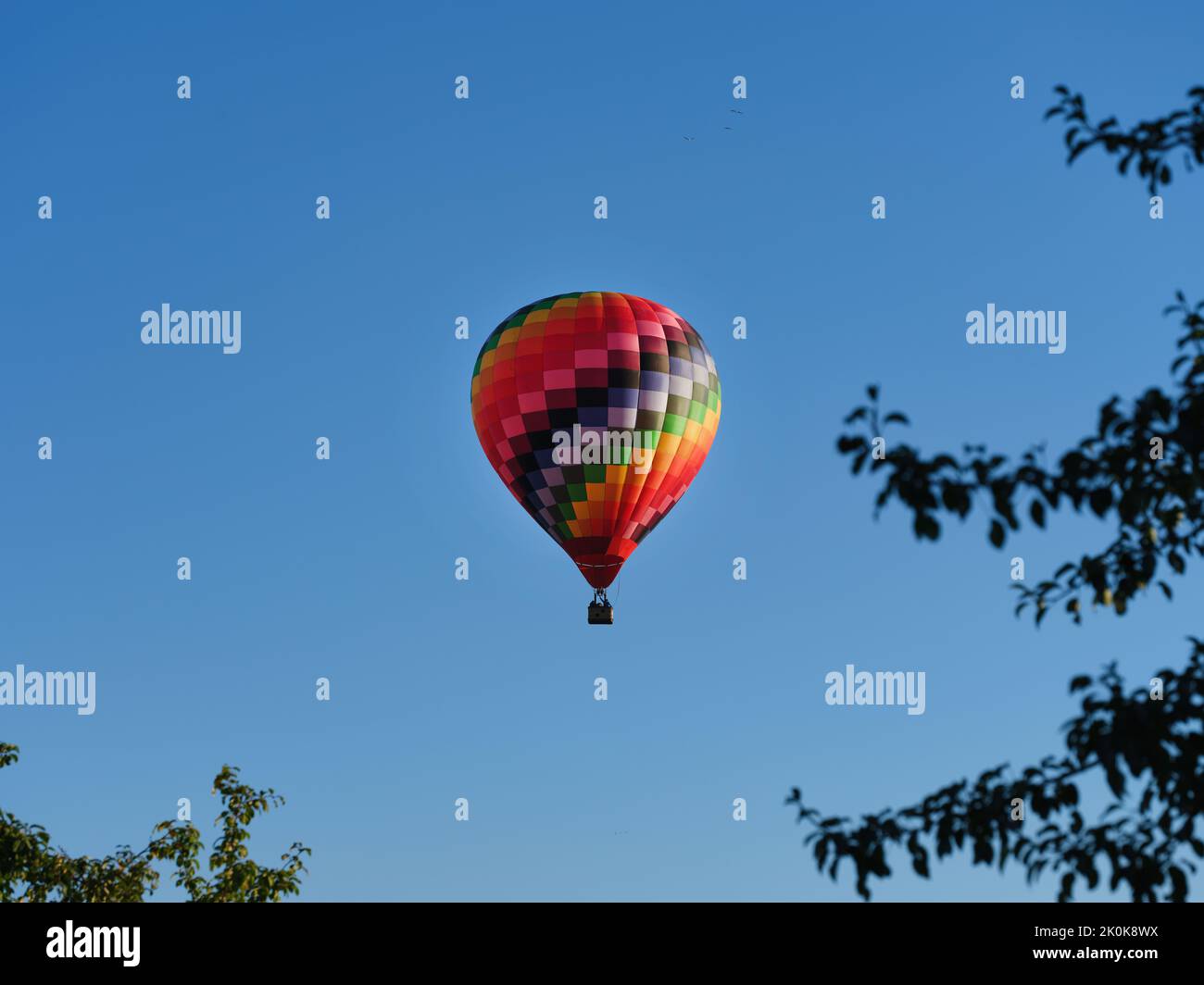 A colorful hot air balloon flying through the blue sky Stock Photo