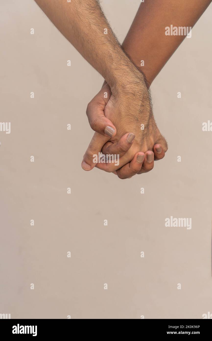 Unrecognizable couple holding hands on chest of man in white t shirt during romantic date Stock Photo