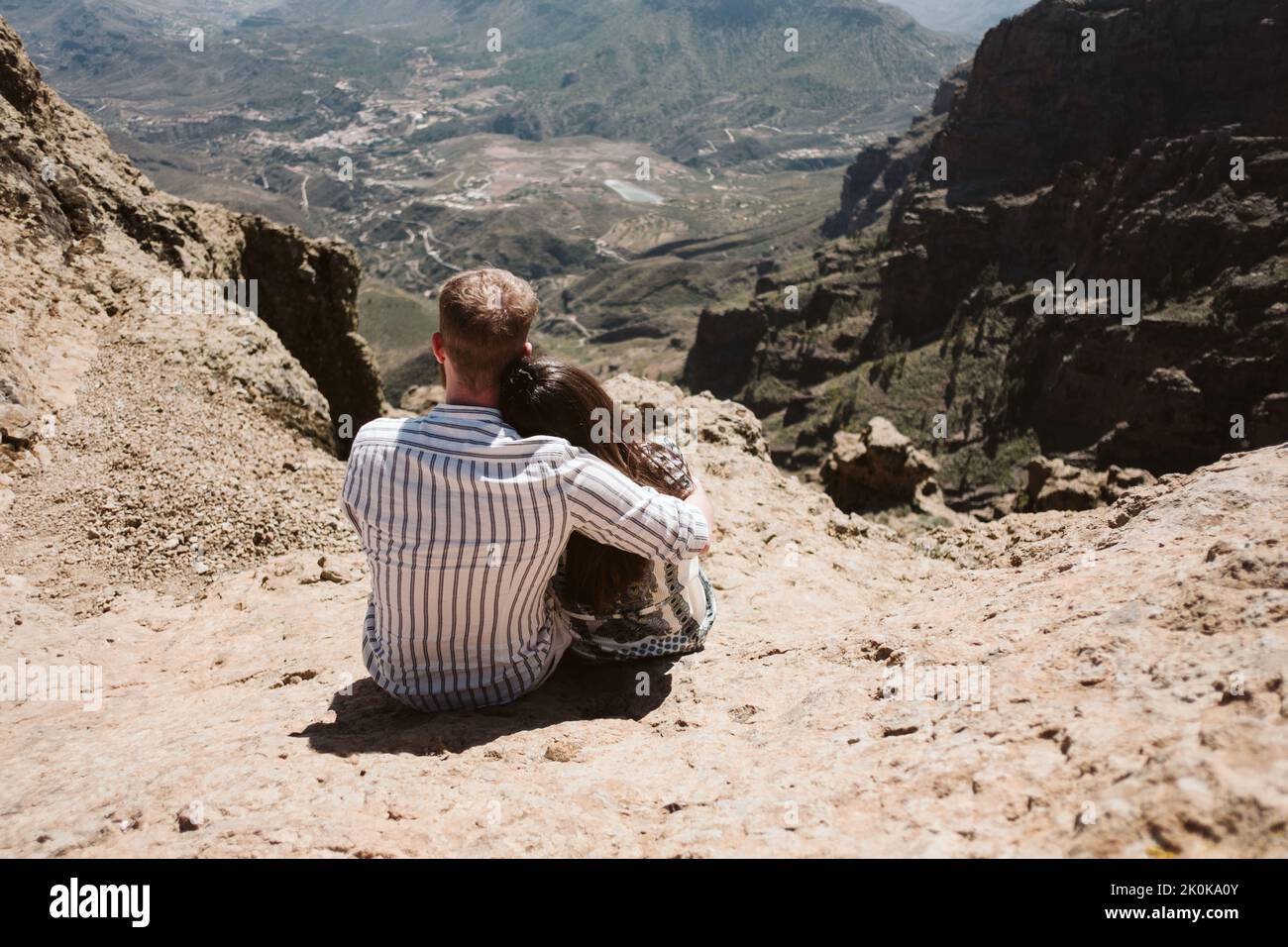 Back view of young couple a man and a woman hugging shyly in mountain ...