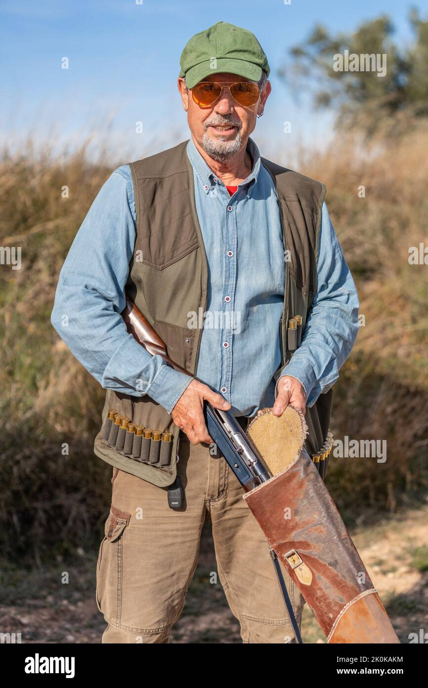 Male hunter in camouflage wear wearing green cap and sunglasses looking