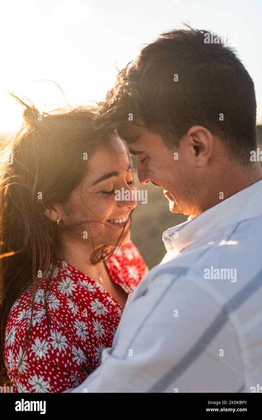 Side view of happy young ethnic female in stylish dress hugging his ...