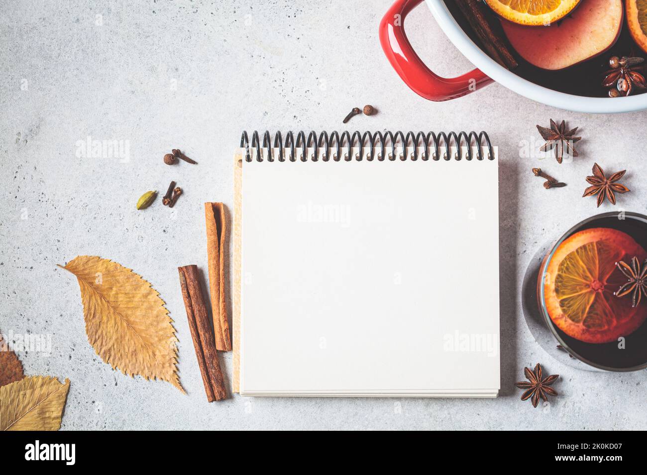 Autumn background with notepad, mulled wine and dry leaves, mock up, copy space, flat lay. Stock Photo
