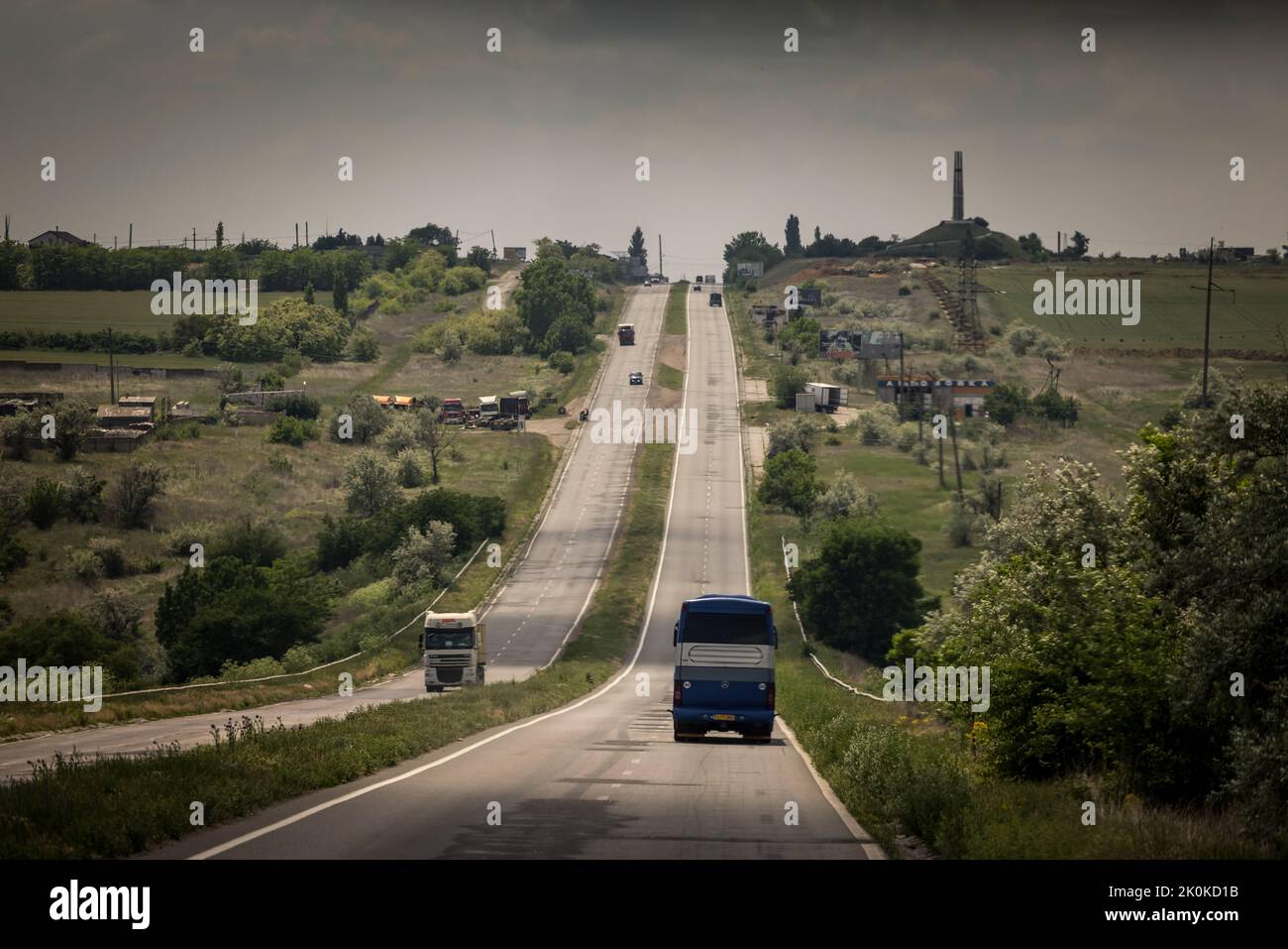 Buses with Ukrainian refugees drive around one of the numerous checkpoints on the M14 road near Mykolaiv, which were set up by the Ukrainian army to control traffic. The buses are used for evacuation of about 110 refugees who want to leave the combat zone in Mykolaiv oblast. The refugees will first be taken to Chisinau in Moldova. Most of them then want to continue their journey to Germany. Stock Photo