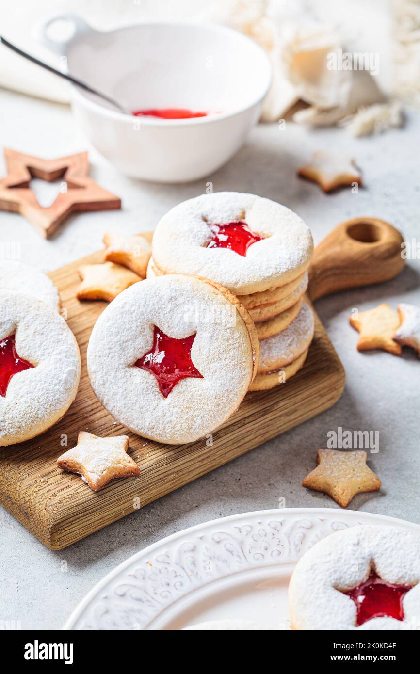 Christmas strawberry linzer cookies on a wooden board. Festive dessert, winter treat. Stock Photo