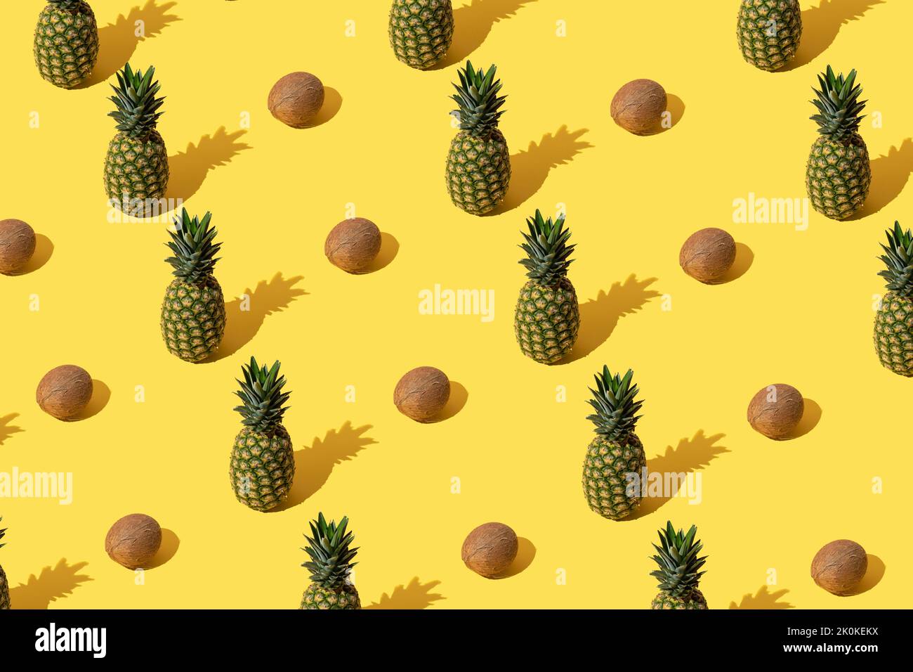 Summer pattern with pineapples and coconuts on yellow background. Stock Photo