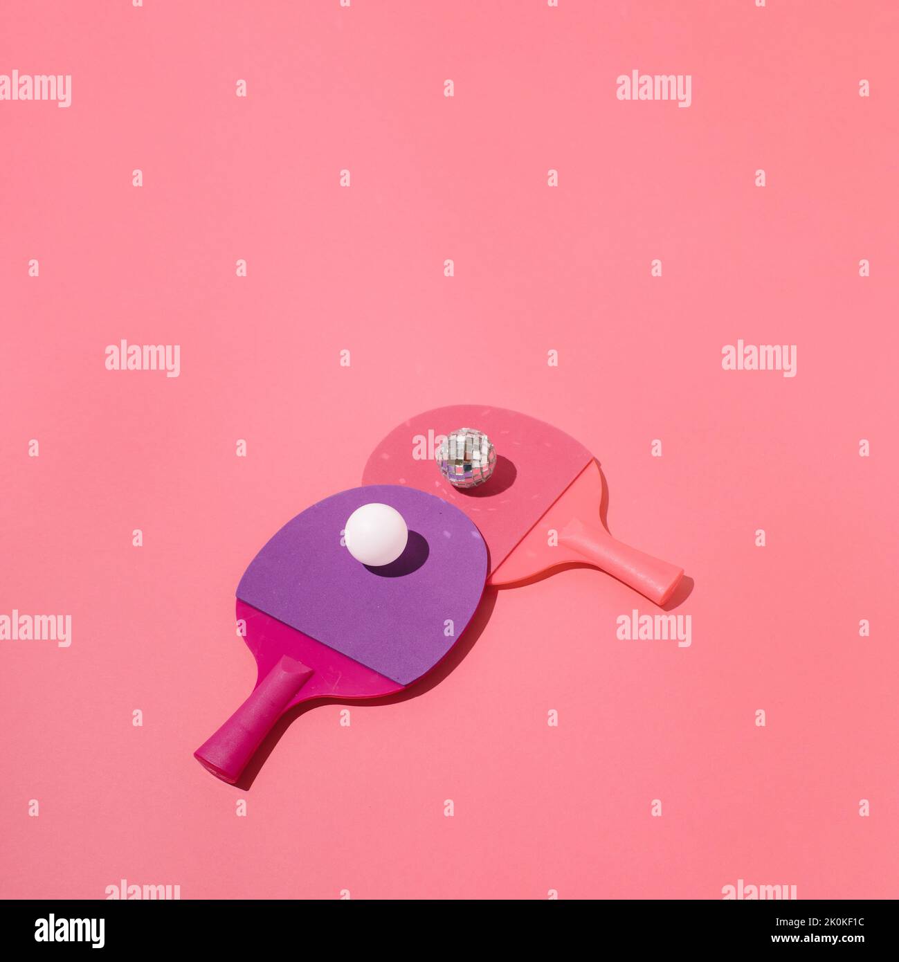 Two table tennis rackets with white ping pong ball and shiny disco ball