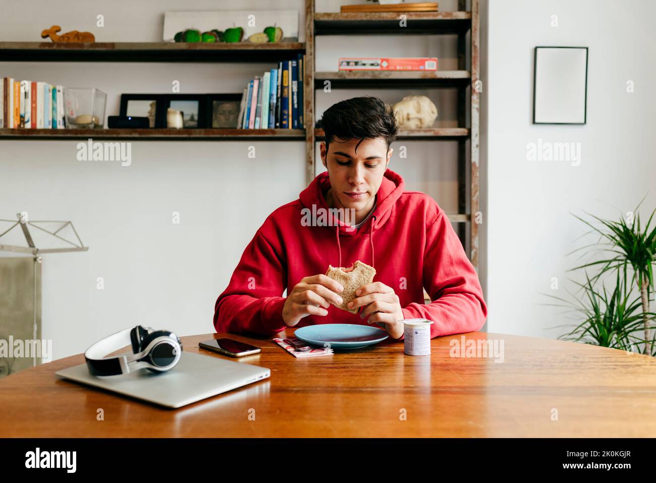 Handsome thoughtful caucasian man eating at home while having lunch break from working with laptop on the table Stock Photo