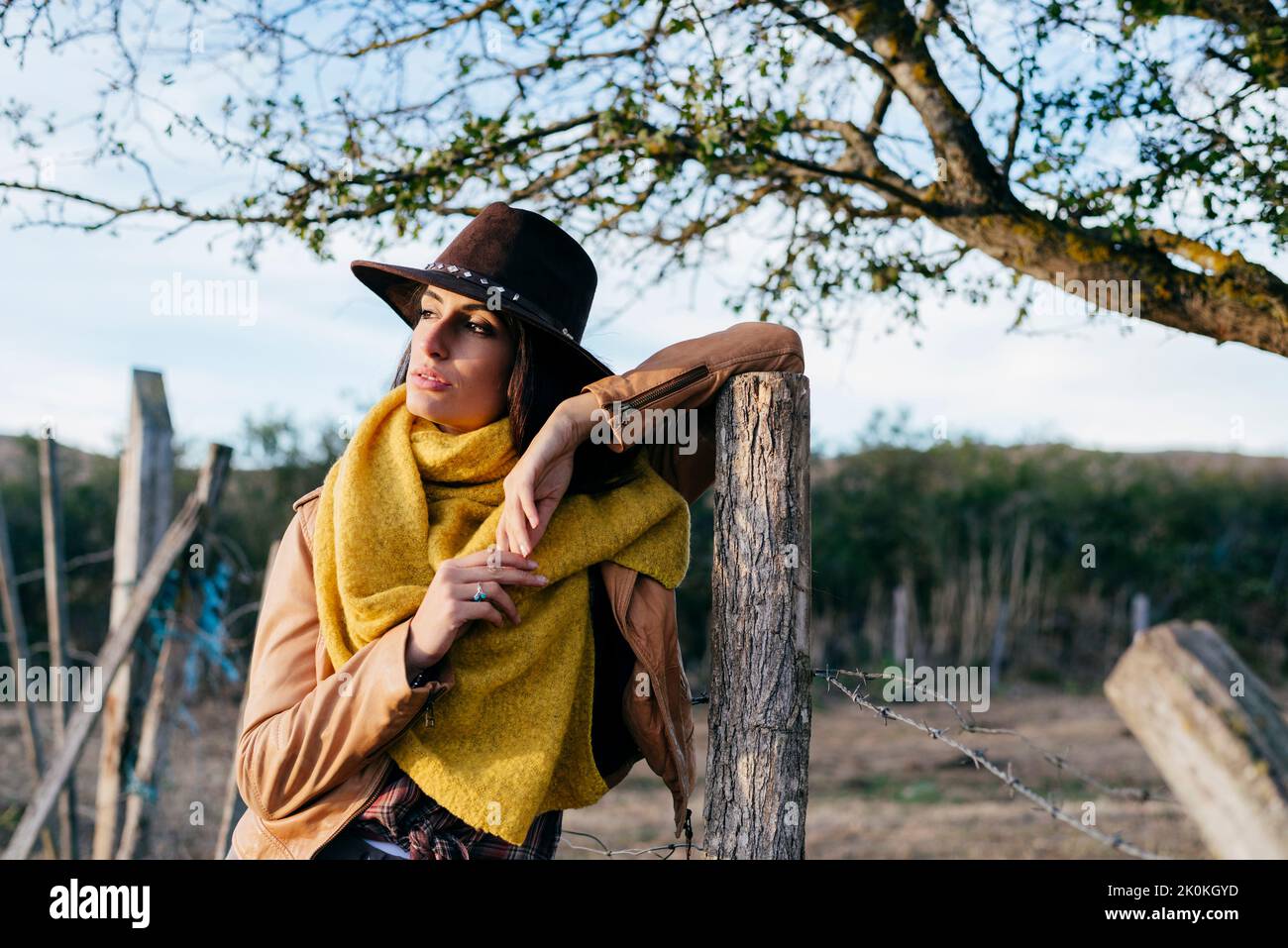 Beautiful trendy brunette in colorful scarf and brown cowboy hat ...