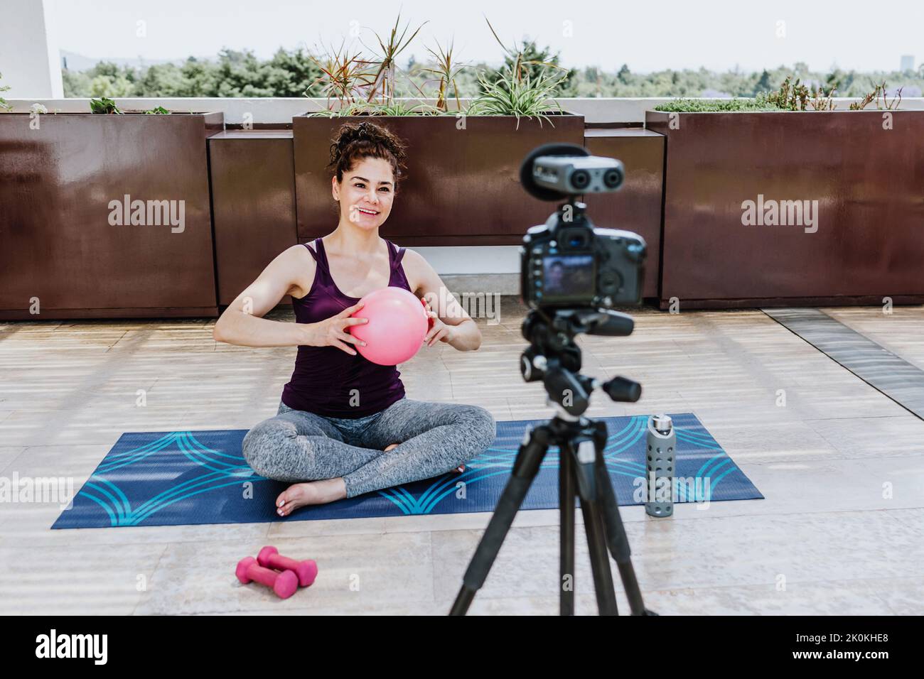 Full body of positive young female athlete in sportswear sitting on mat ...