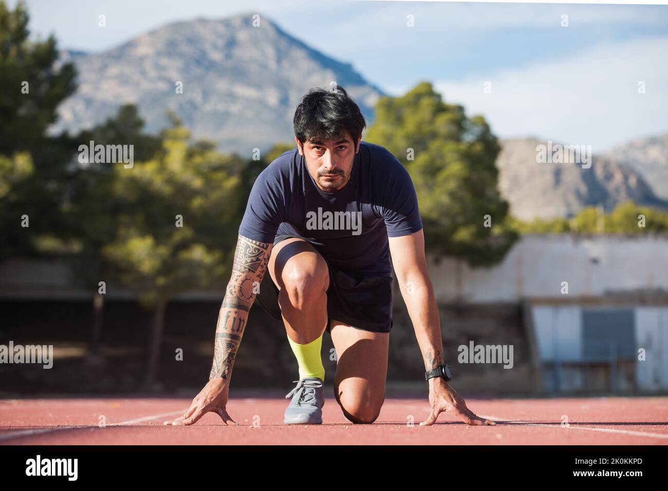 Front view of Hispanic male professional runner standing in crouch ...