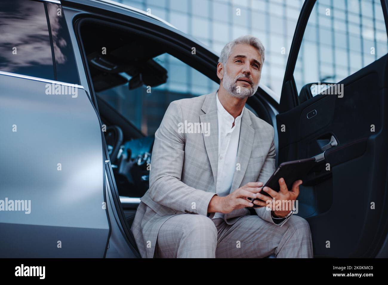 Businessman using tablet while charging car at electric vehicle