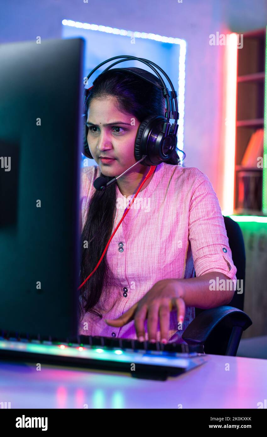 Woman playing live video game on computer by talking to players on headphones at home - concept of live streamer, vlogger and tournament. Stock Photo