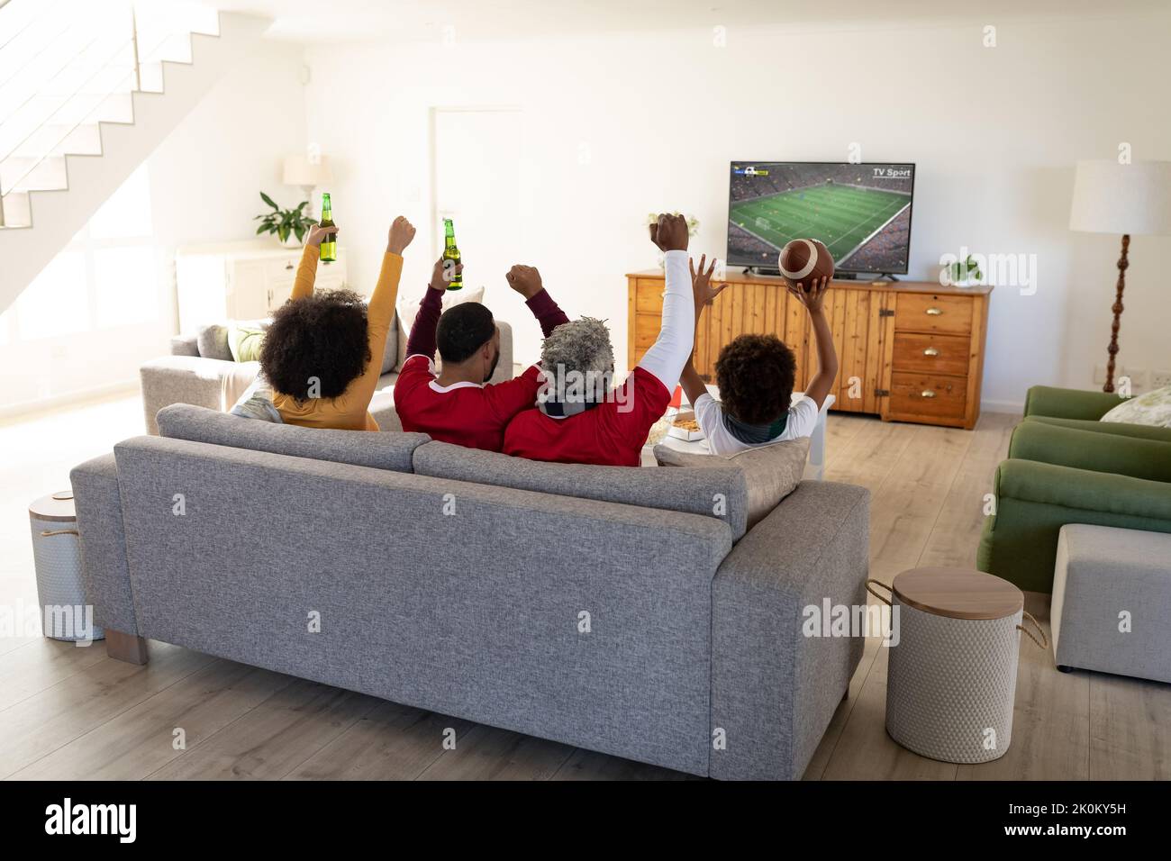 African american family sitting on the couch and watching football match on laptop Stock Photo